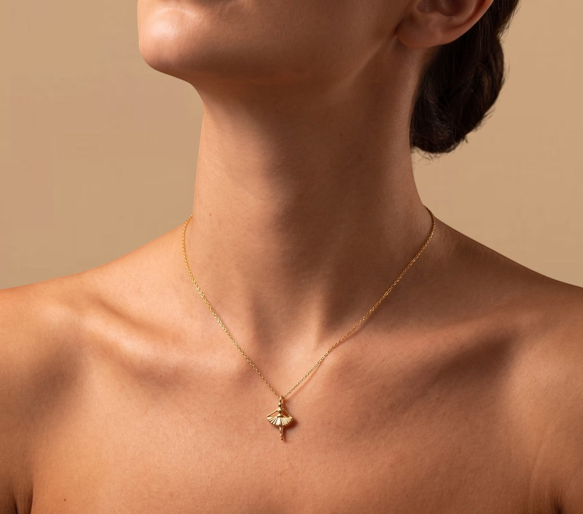 RITI delicate gold ballerina necklace with a fan-shaped skirt and intricate engravings. Minimalist pendant.