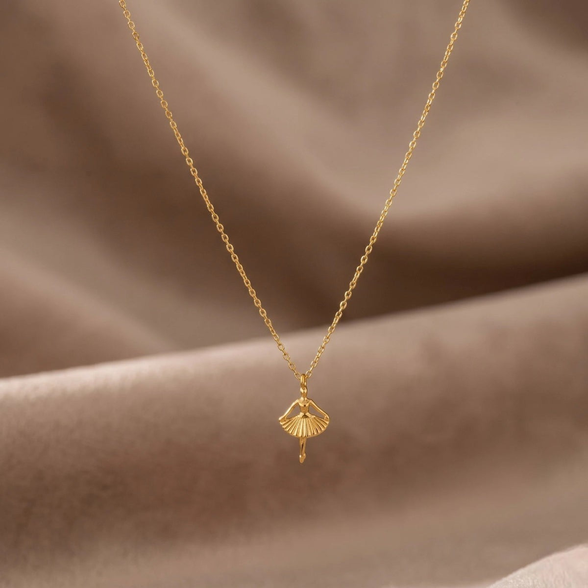 RITI delicate gold ballerina necklace with a fan-shaped skirt and intricate engravings. Minimalist pendant.