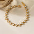 RITI gold tennis bracelet featuring heart-cut cubic zirconia stones in a bezel setting on a soft cream background.