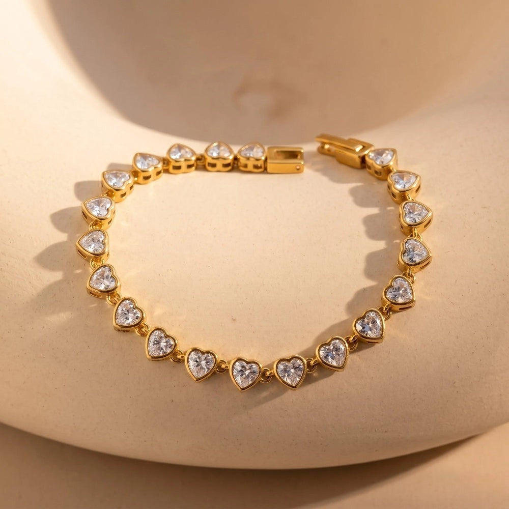 RITI gold tennis bracelet featuring heart-cut cubic zirconia stones in a bezel setting for a romantic, elegant look.
